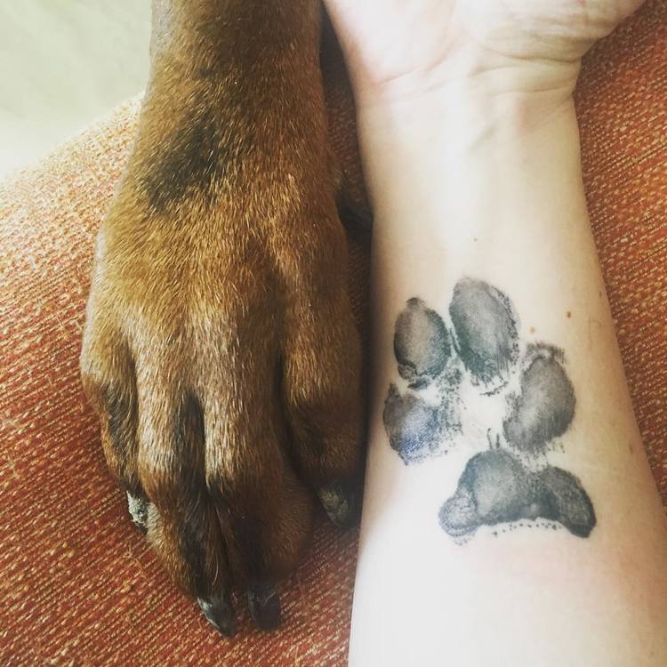 Symbolism: Loyalty, companionship, love, protection, remembrance.  Description: A realistic dog paw tattoo with the name 