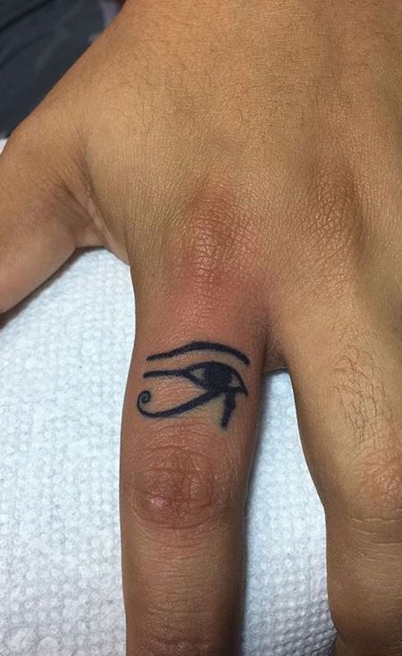 Evil eye tattoo on the right middle finger.