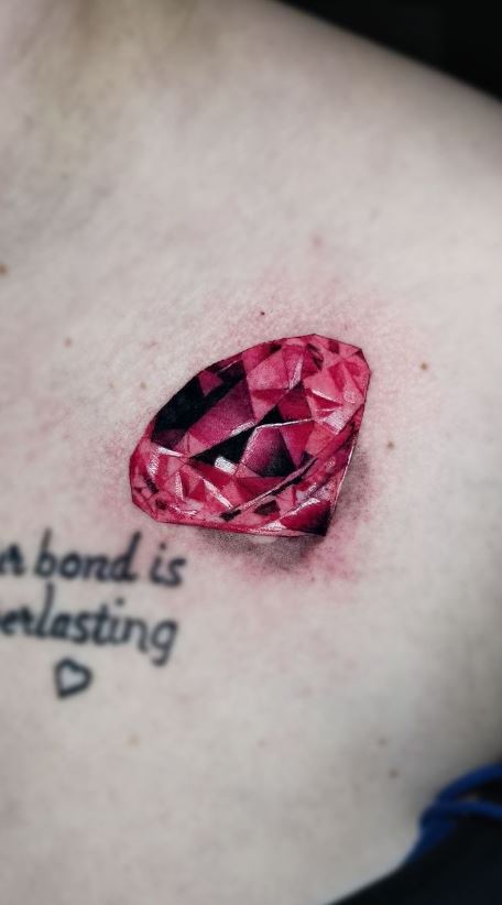 Sketchy ruby stone tattoo on the left inner forearm